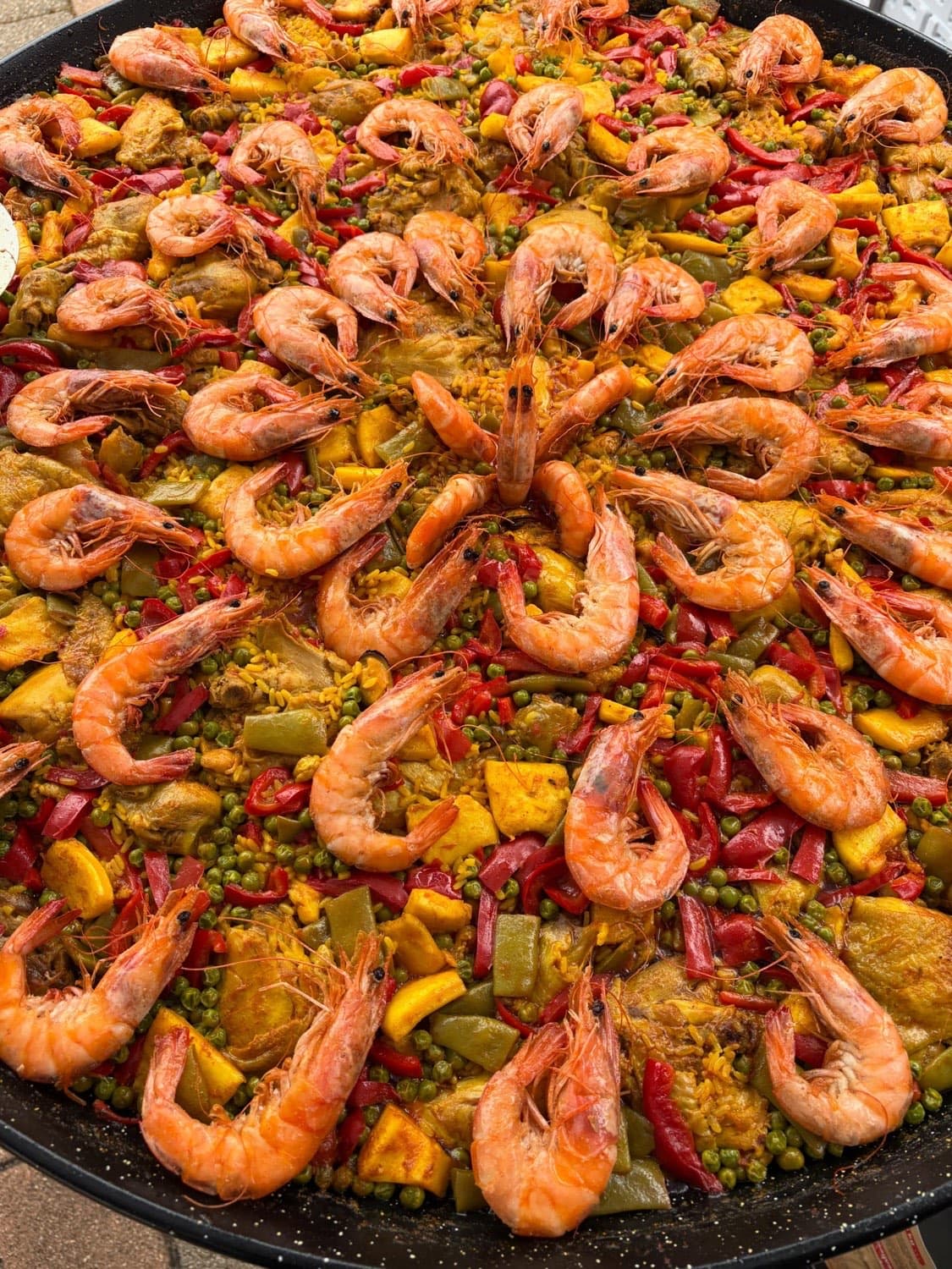 Paella géante aux gambas cuisinée par Casa Filipe, riz safrané, poivrons et petits pois
